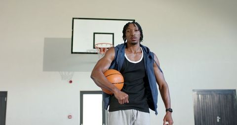 Confident male basketball player in gym holding ball