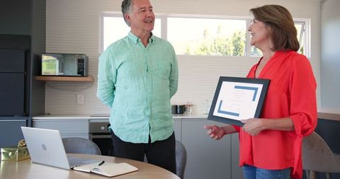 Senior couple holding picture frame in contemporary kitchen