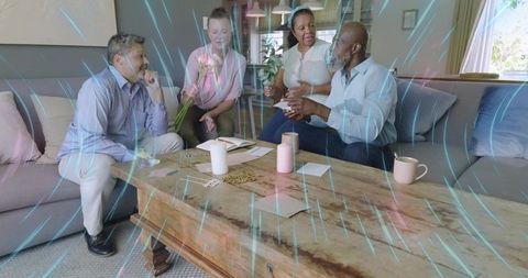 Mature adults chatting and sharing letters around rustic coffee table in bright living room