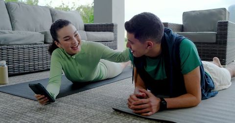 Couple enjoys outdoor workout break with gadgets on patio