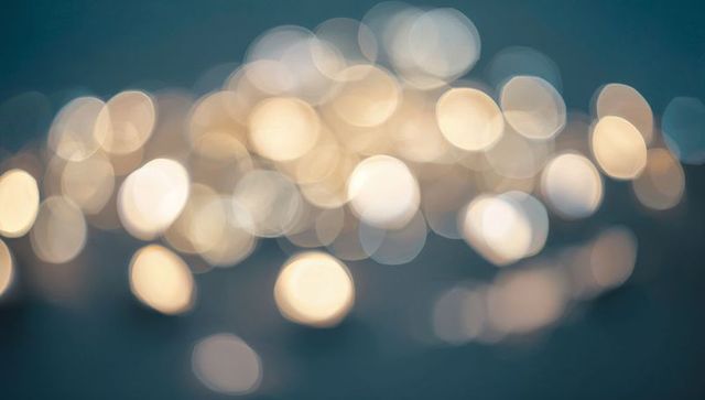 Glowing Bokeh Orbs Floating Over Soft Blue-Gray Background, Dreamy Warm Fairy Lights
