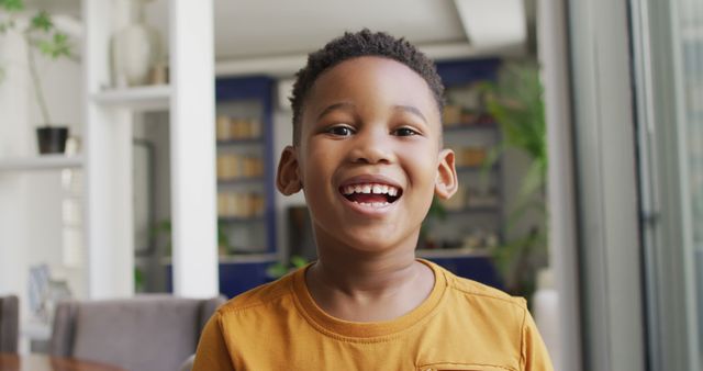 Young boy smiling indoors with a cheerful expression. Ideal for family-oriented content, lifestyle blogs, educational materials, or advertisements promoting children's products, happiness, or well-being.