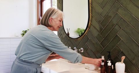 Senior Woman Practicing Hand Hygiene in Modern Bathroom