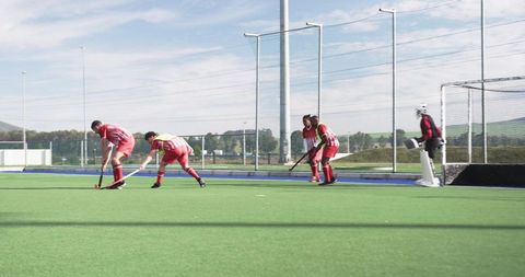 Male hockey players competing on outdoor field