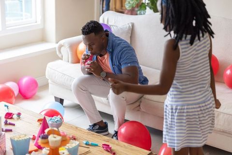 African american father blowing balloons with daughter preparing colorful birthday party