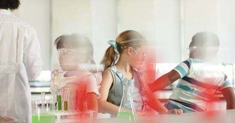 Elementary students conducting colorful science experiment wearing goggles with teacher