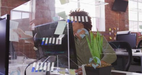 Creative team member placing sticky notes on glass partition in modern office planning