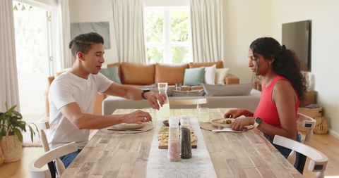 African american couple enjoying cozy sunlit lunch pouring drink at rustic dining table