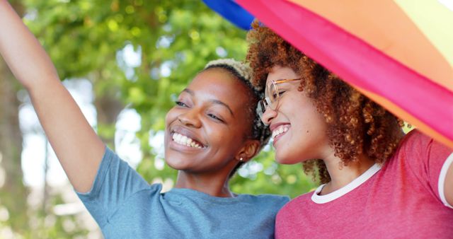 Couple smiling and embracing under rainbow flag. Perfect for representing love, LGBTQ community, pride celebrations, unity, and outdoor activities promoting acceptance and happiness.