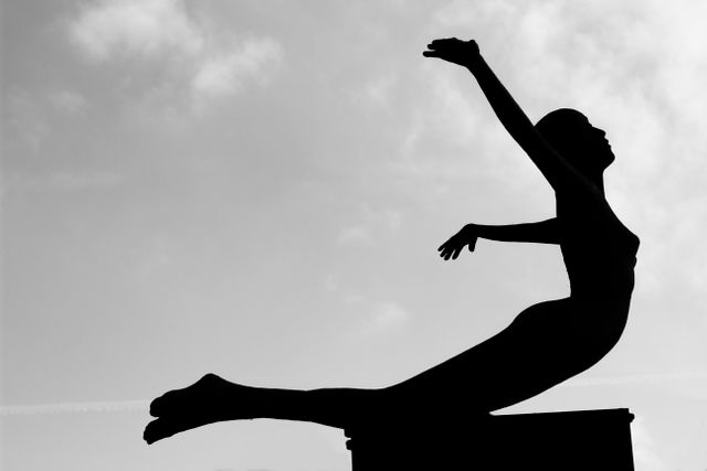 Silhouette of female statue diving against sky. Ideal for concepts of freedom, art, sculpture, and outdoor exhibitions. Useful for blog posts, art and sculpture websites, or inspirational materials.