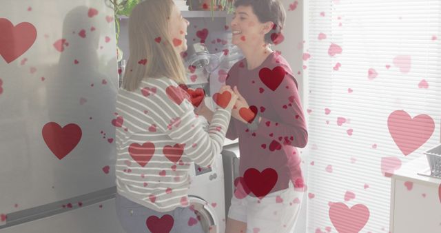 Image of heart emojis over happy caucasian female couple in love dancing. Love, romance and celebration concept digitally generated image.