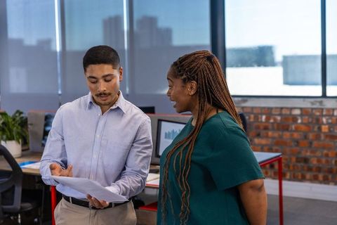 Diverse Coworkers Analyzing Documents in Modern Office