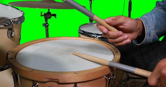 Hands on drummer playing drum against green screen