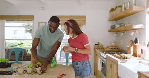 Diverse Couple Gardening Indoors with Eco-Friendly Techniques