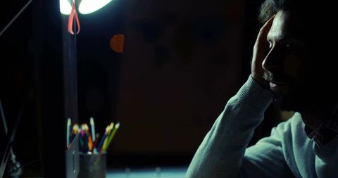 Pensive man under desk lamp contemplative study ambiance