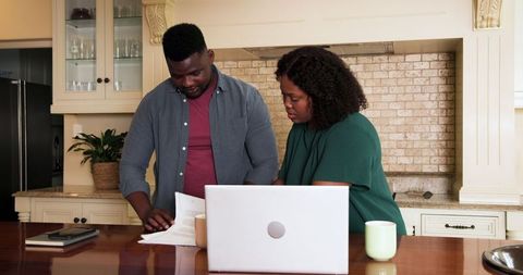 Couple reviewing financial documents together in kitchen