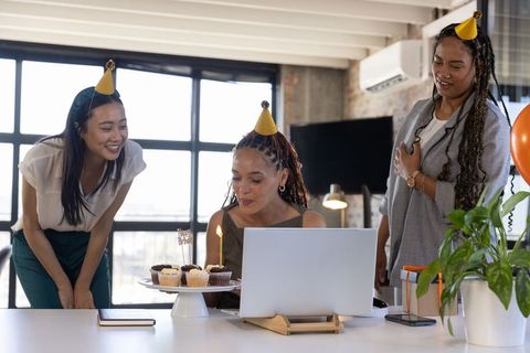Coworkers Celebrating Birthday Around Laptop with Cupcakes and Candles
