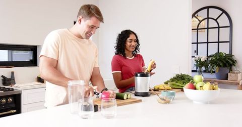 Diverse Couple Making Green Smoothie at Modern Kitchen Island