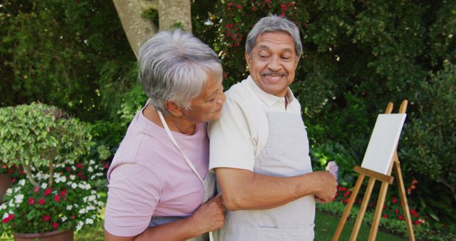 Image of happy biracial senior couple painting in garden. active retirement lifestyle, senior relationship, hobby and spending time together.