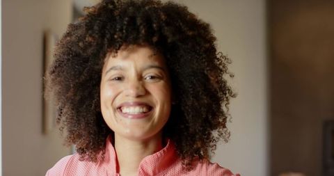 Warm smiling african american woman with natural curly hair wearing coral zip-up top