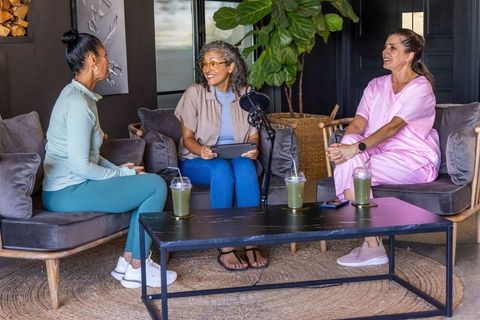 Female colleagues recording casual wellness podcast in cozy clinic lounge