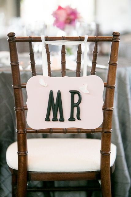 Elegant wedding reception chair decorated with a 'Mr' sign in black font on a wooden chair with a neutral background. Ideal for content related to wedding planning, decorations, bride and groom seating arrangements, and bridal resources.