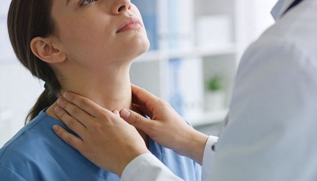 Doctor palpating patient neck for thyroid and cervical exam during clinical consultation