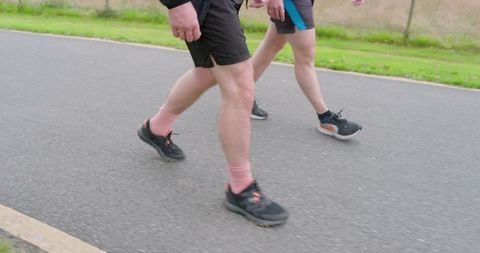 Two people jogging on a paved path in athletic apparel