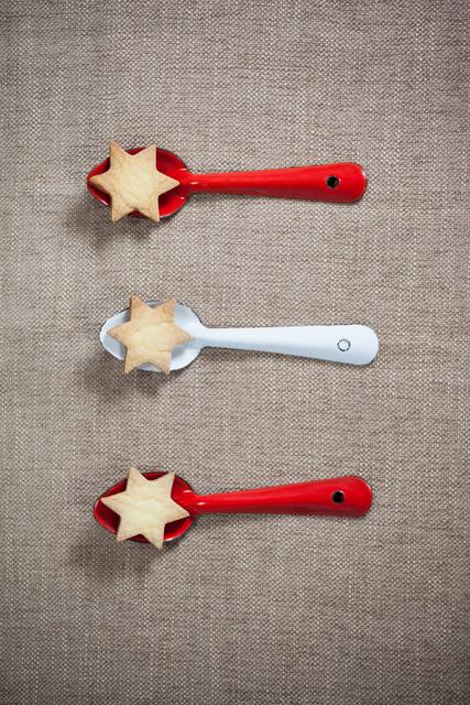 Red and white spoon with christmas cookies arranged on tablecloth