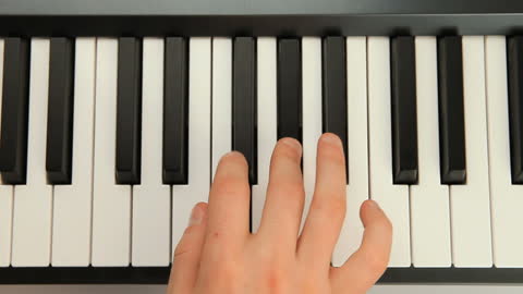 Close-Up of Hand Playing Piano Keys in Music Studio