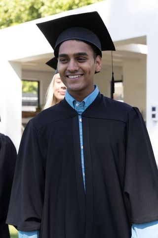 Smiling Graduate in Cap and Gown at Outdoor Ceremony