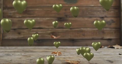 Olive Green Metallic Heart Balloons Floating Over Rustic Wooden Floor with Fallen Leaves