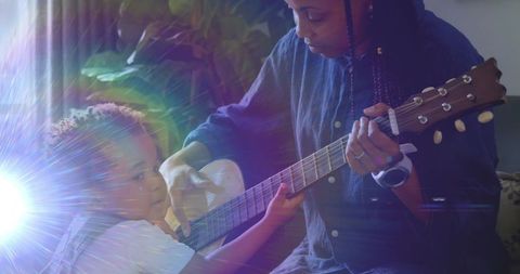 Mother Guiding Child Learning to Play Guitar at Home