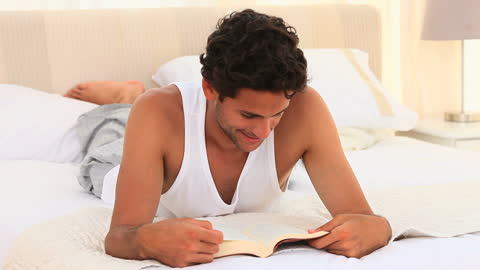 Man Relaxing on Bed Reading Book for Leisure