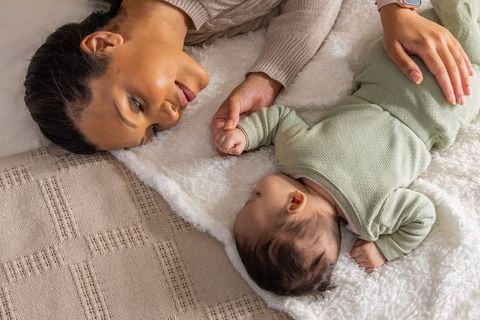 African american mother bonding with newborn on plush blanket, cozy neutral nursery moment
