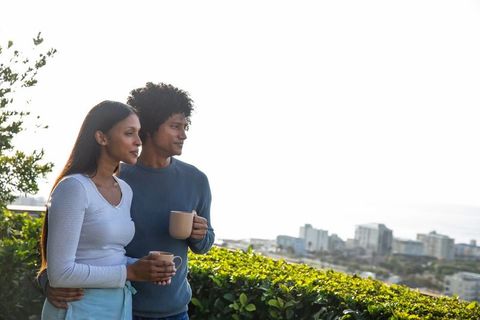 Couple Enjoying Coffee with Scenic City Views on a Balcony