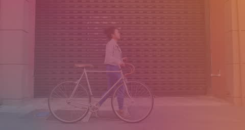 Woman Walking with Bicycle and Checking Smartphone on Urban Street