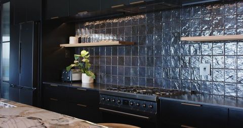 Contemporary Black Kitchen with Glossy Square-Tile Backsplash, Gas Range and Marble Island