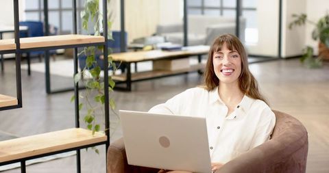 Smiling woman working on laptop at cozy office lounge