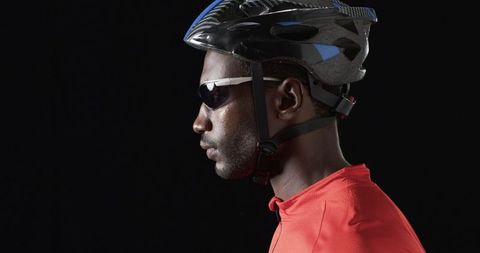 Focused Cyclist in Helmet and Gear Against Black Background