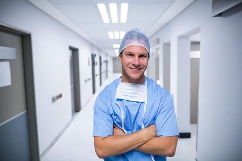 Confident Male Nurse in Hospital Corridor Wearing Surgical Scrubs