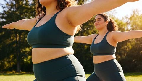 Curvy women stretching outdoors in teal activewear practicing yoga on sunny park grass
