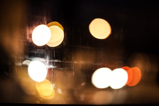 Blurry bokeh of city lights glowing at night creates an abstract urban ambiance. Ideal for backgrounds, wallpapers, or artistic elements in graphic design projects.