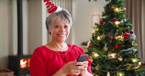 Cheerful Woman in Festive Atmosphere Texting on Smartphone