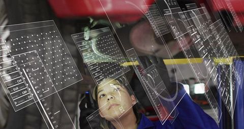 Automotive engineer inspecting vehicle using augmented reality overlays in service bay