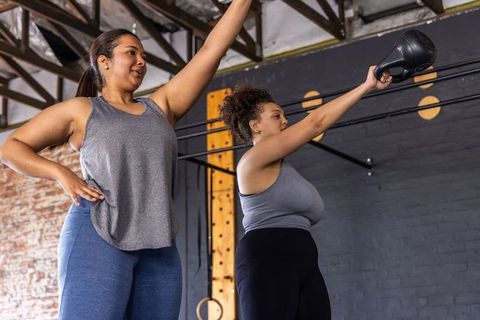 African american women lifting kettlebell during strength training in industrial gym