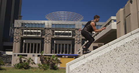 Man Practicing Parkour by Modern Building on Sunny Day