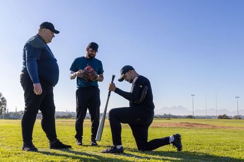 Veteran Coach Guiding Baseball Players in Outdoor Practice — Batting and Field Drills