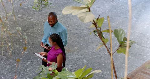 Colleagues Collaborating with Tablet in Modern Foyer