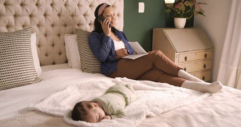 Mom balancing work and care with sleeping baby nearby